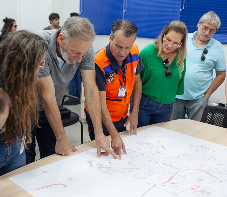 Equipe municipal reunida em torno de um mapa durante oficina de planejamento